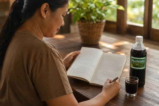 Person reviewing a wellness journal over three months alongside a glass of PhilNONI noni juice